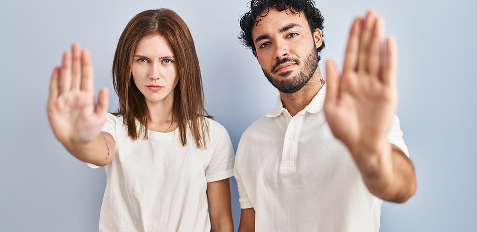 Frau und Mann mit erhobener Hand zum Stopp – typische Todsünden während der Kontaktsperre
