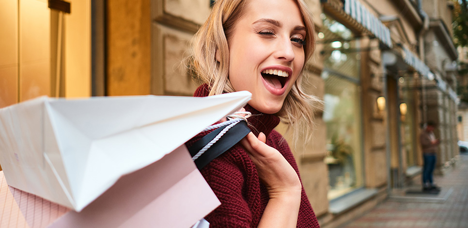 Glückliche Frau mit Einkaufstüten – symbolisch für den Handlungsplan, um Männer besser zu verstehen